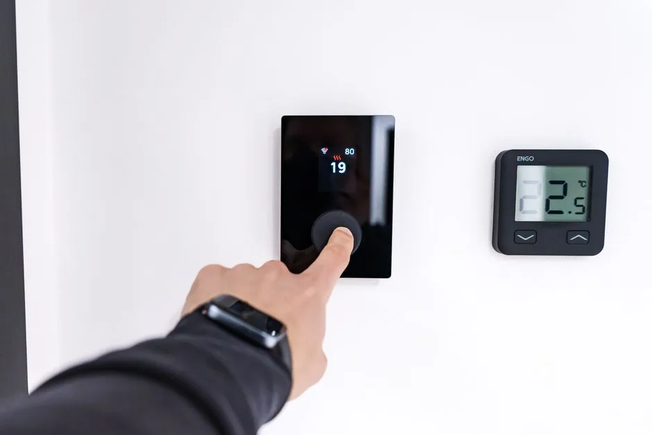 A hand adjusting a smart thermostat